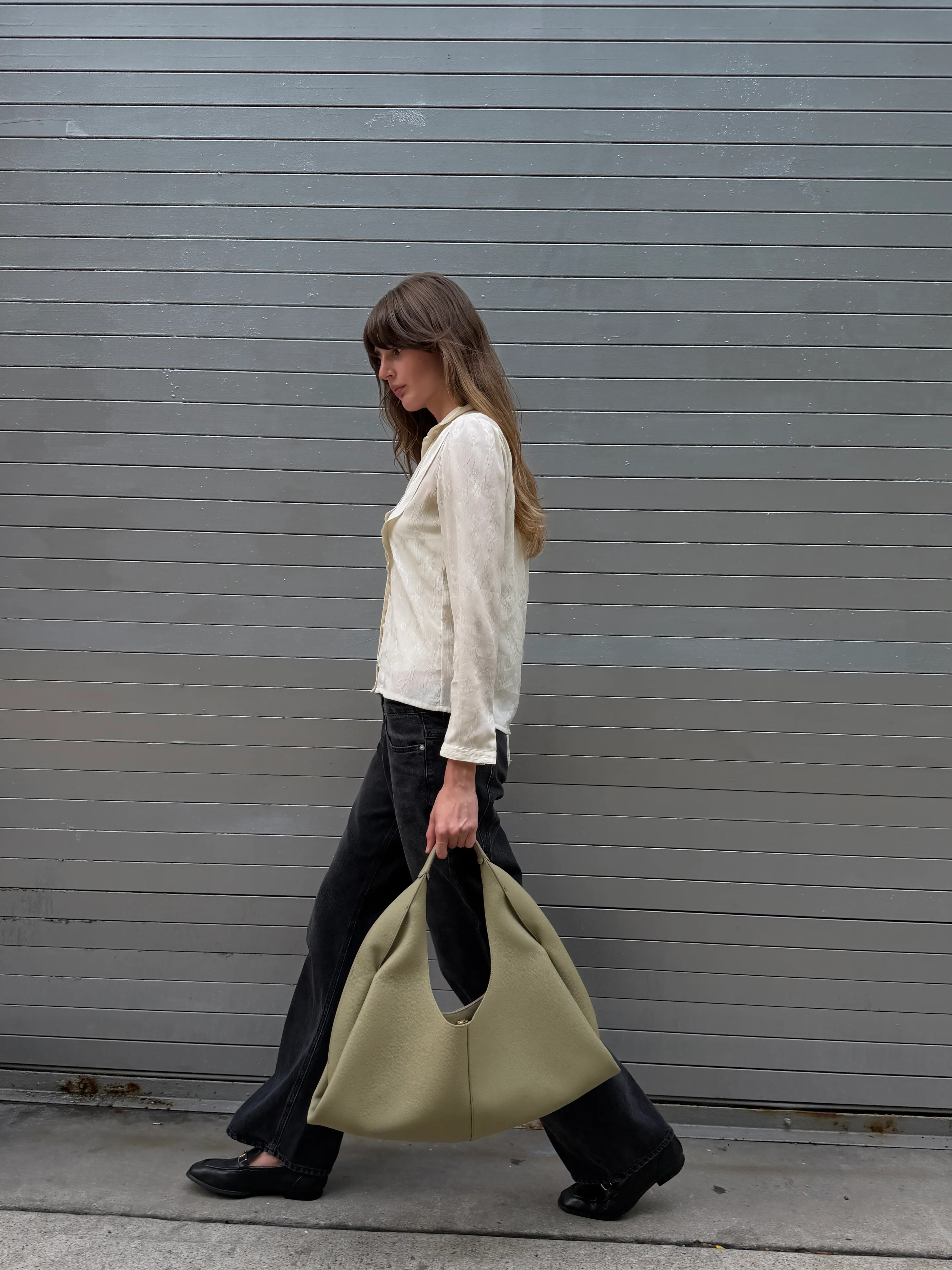 Cream textured blouse with black wide-leg jeans, black loafers, and a large sage green bag.