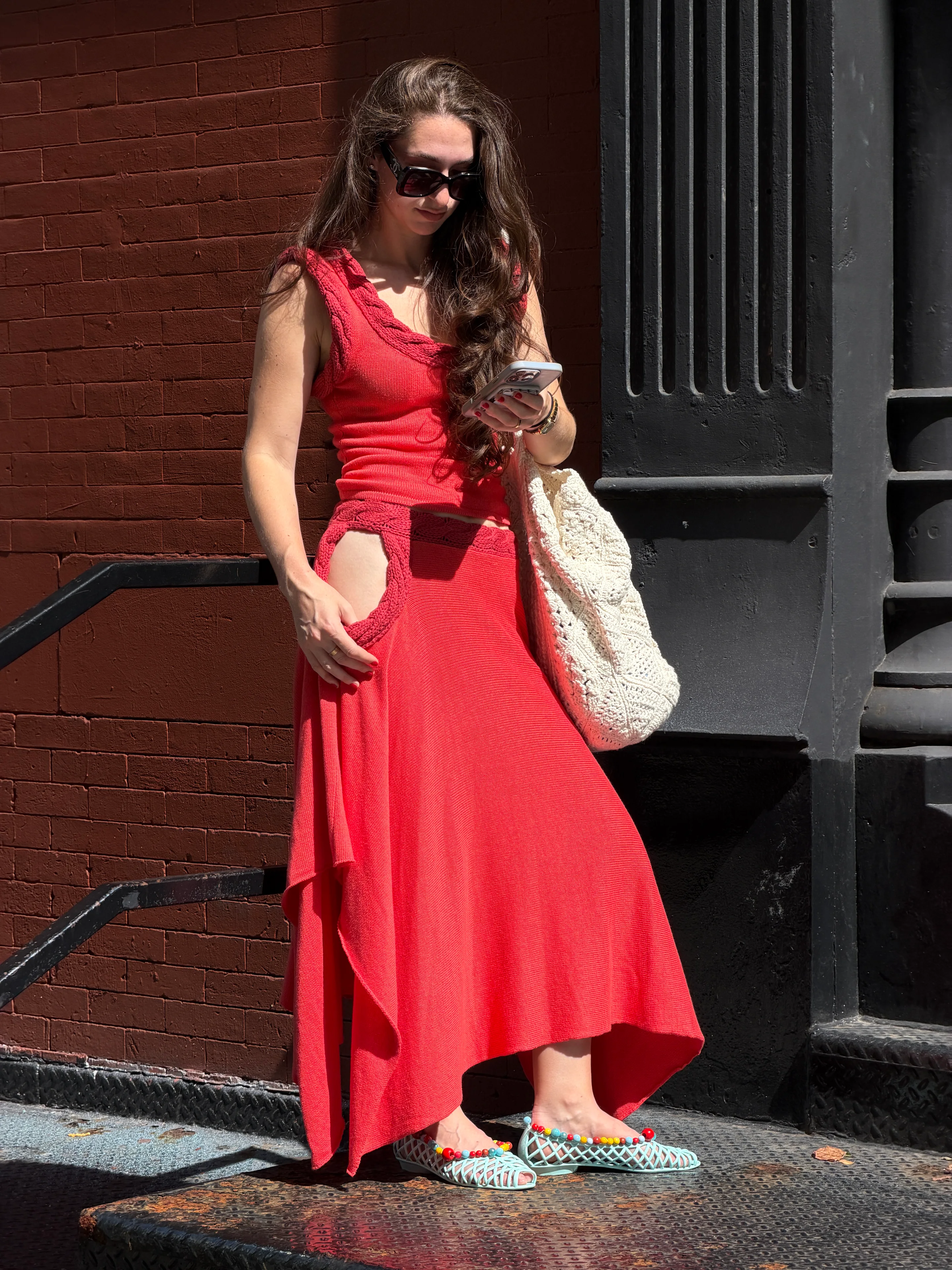 Red knit cut-out top and skirt, crochet bag, beaded jelly sandals.