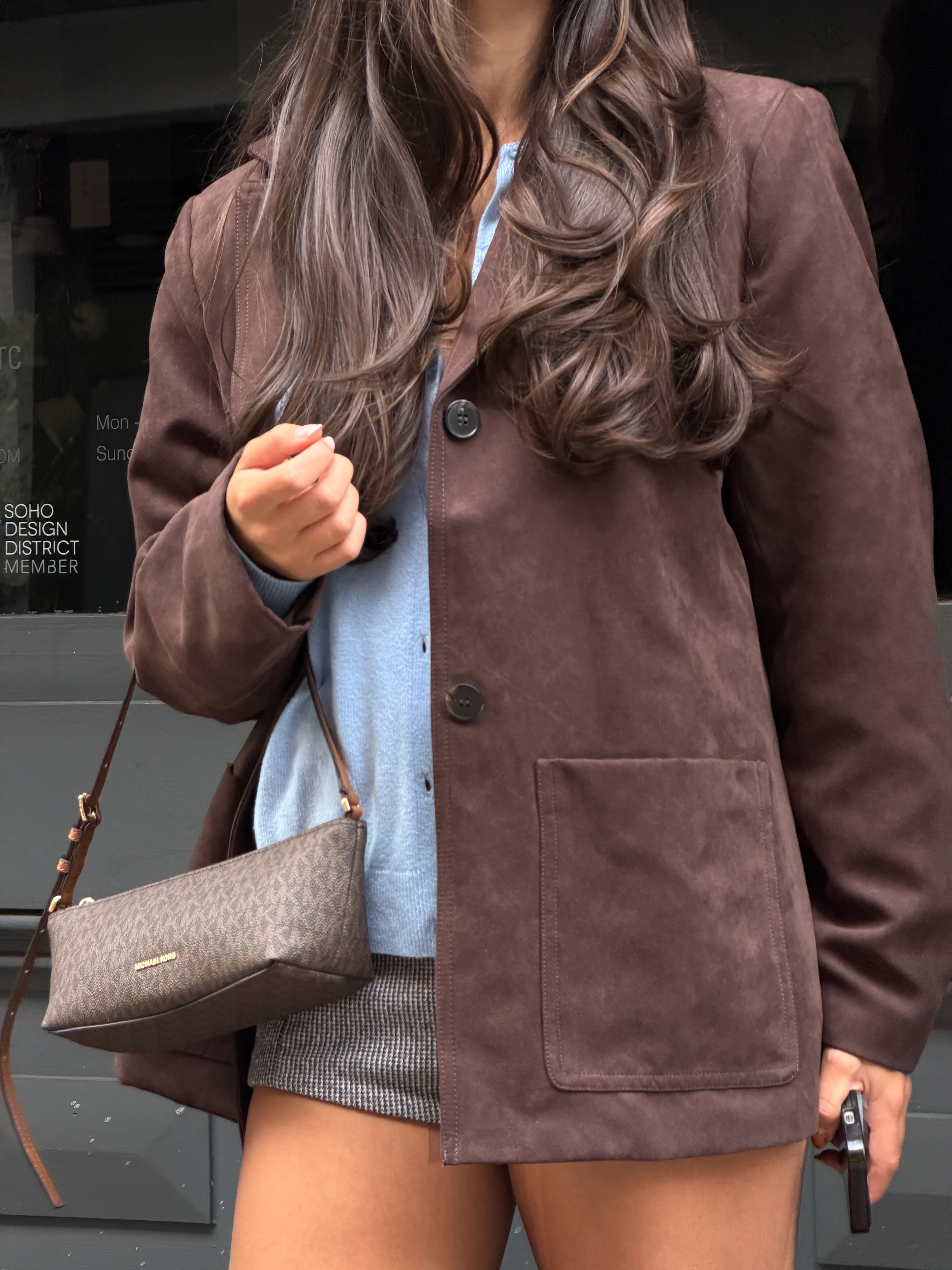 Brown suede blazer, light blue cardigan, plaid skirt, and brown Michael Kors bag.