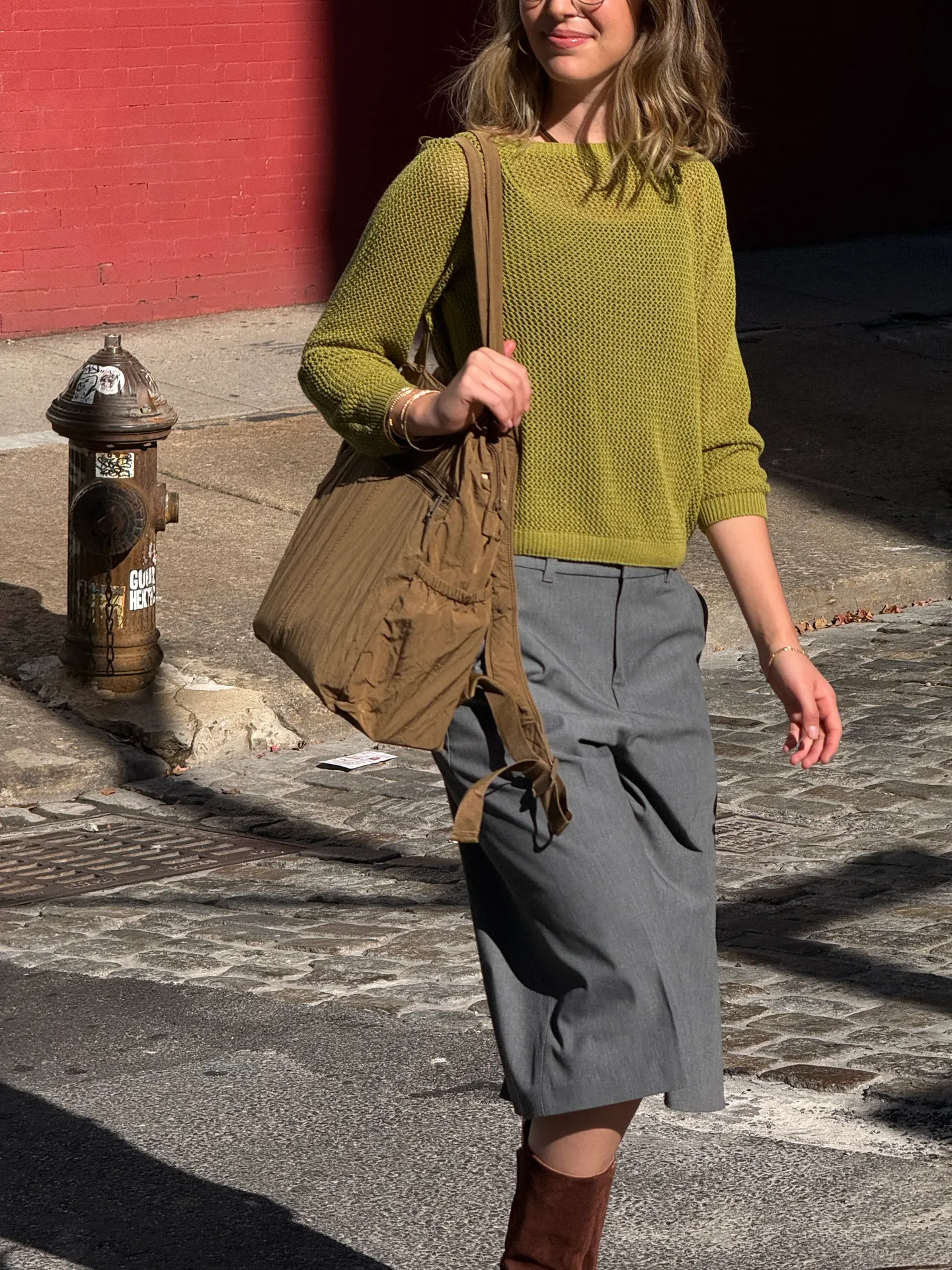 Olive green knit sweater, gray wide-leg pants, brown shoulder bag, and knee-high boots.