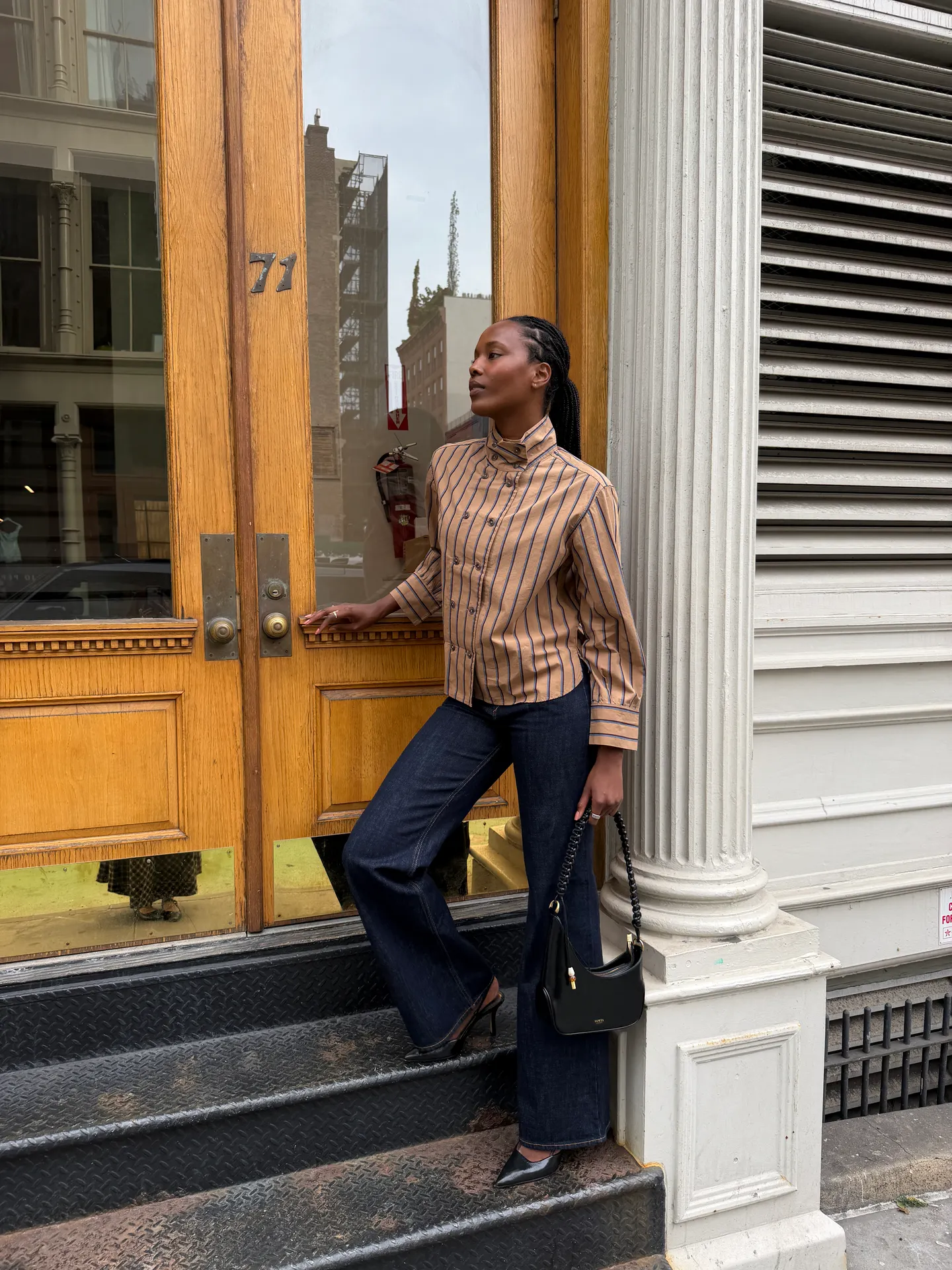 Tan striped button-up shirt, dark wide-leg jeans, black kitten heels, and a black bag.