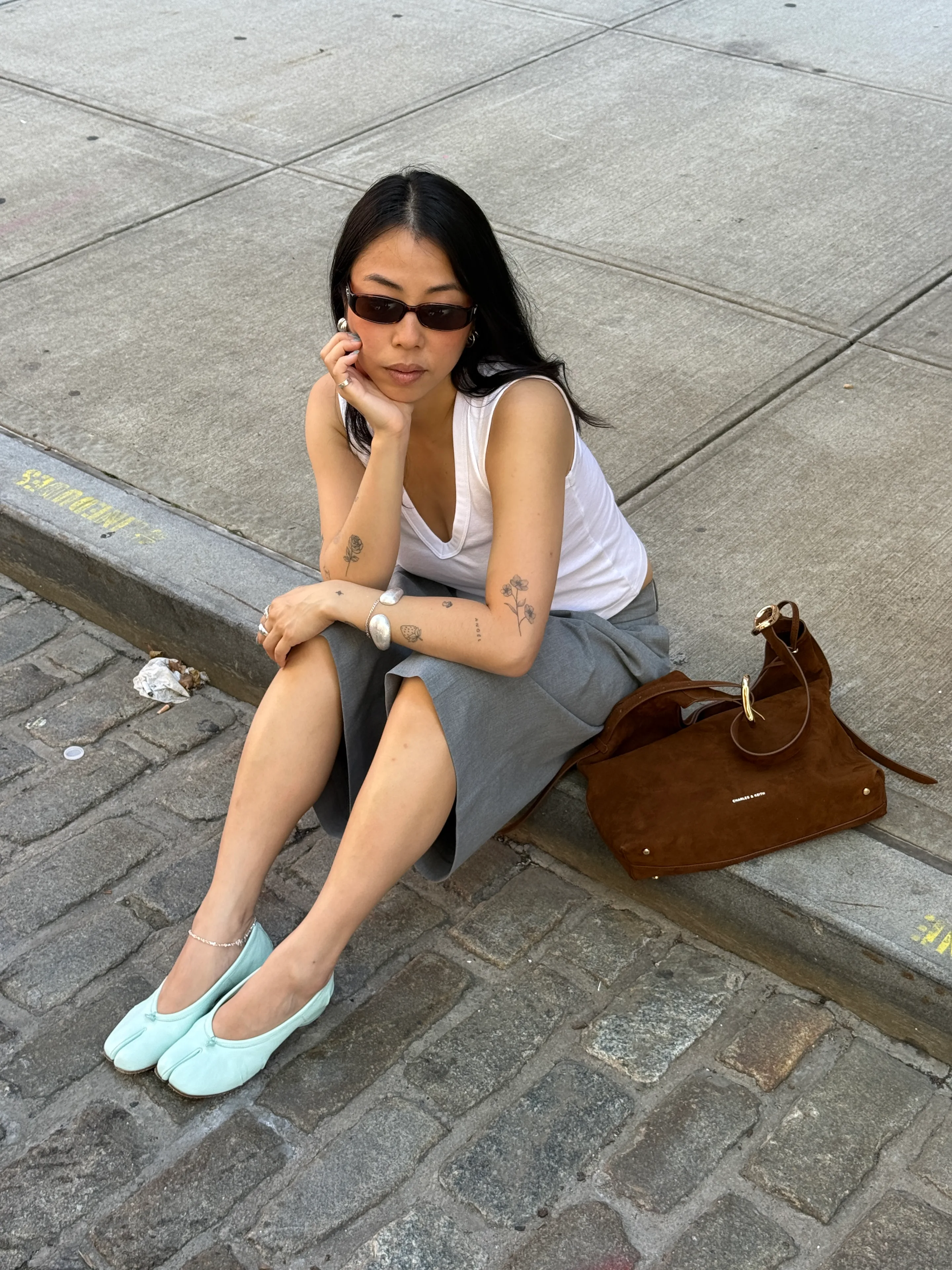 White V-neck tank, grey midi skirt, mint tabi flats, and brown suede bag.