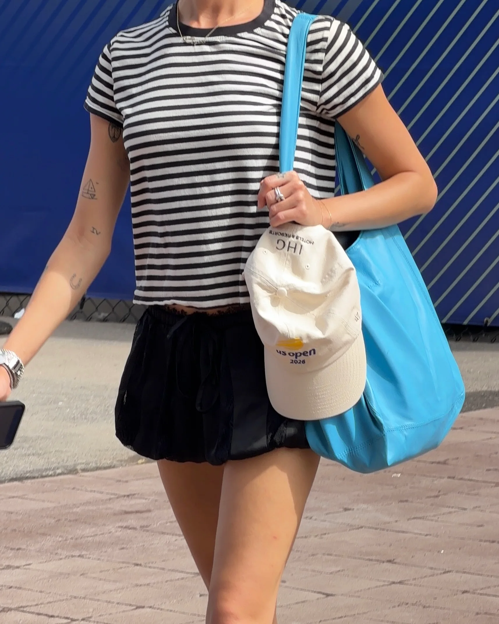 Black and white striped tee, black shorts, turquoise tote bag with a US Open hat.