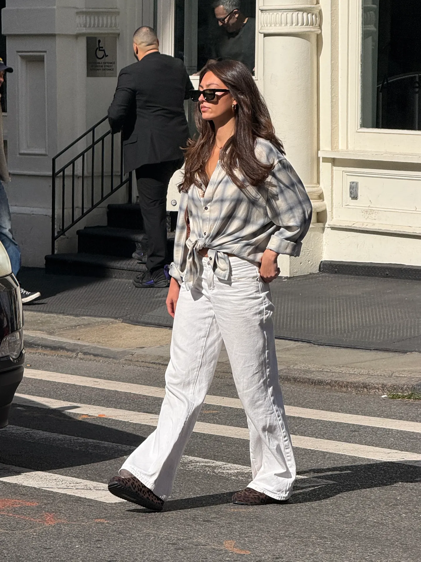 Plaid oversized button-up shirt with white flare jeans and leopard print shoes, walking outside.