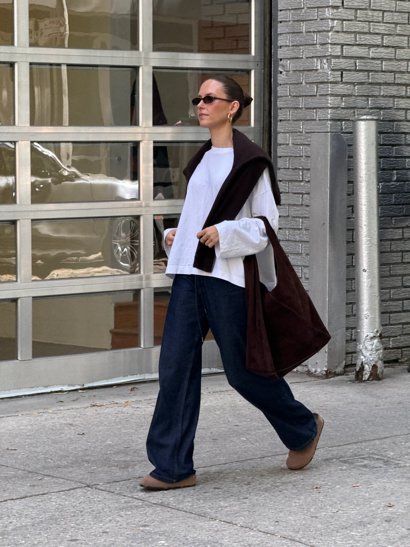 White oversized shirt, dark wash baggy jeans, brown sweater and tote bag, tan mules.
