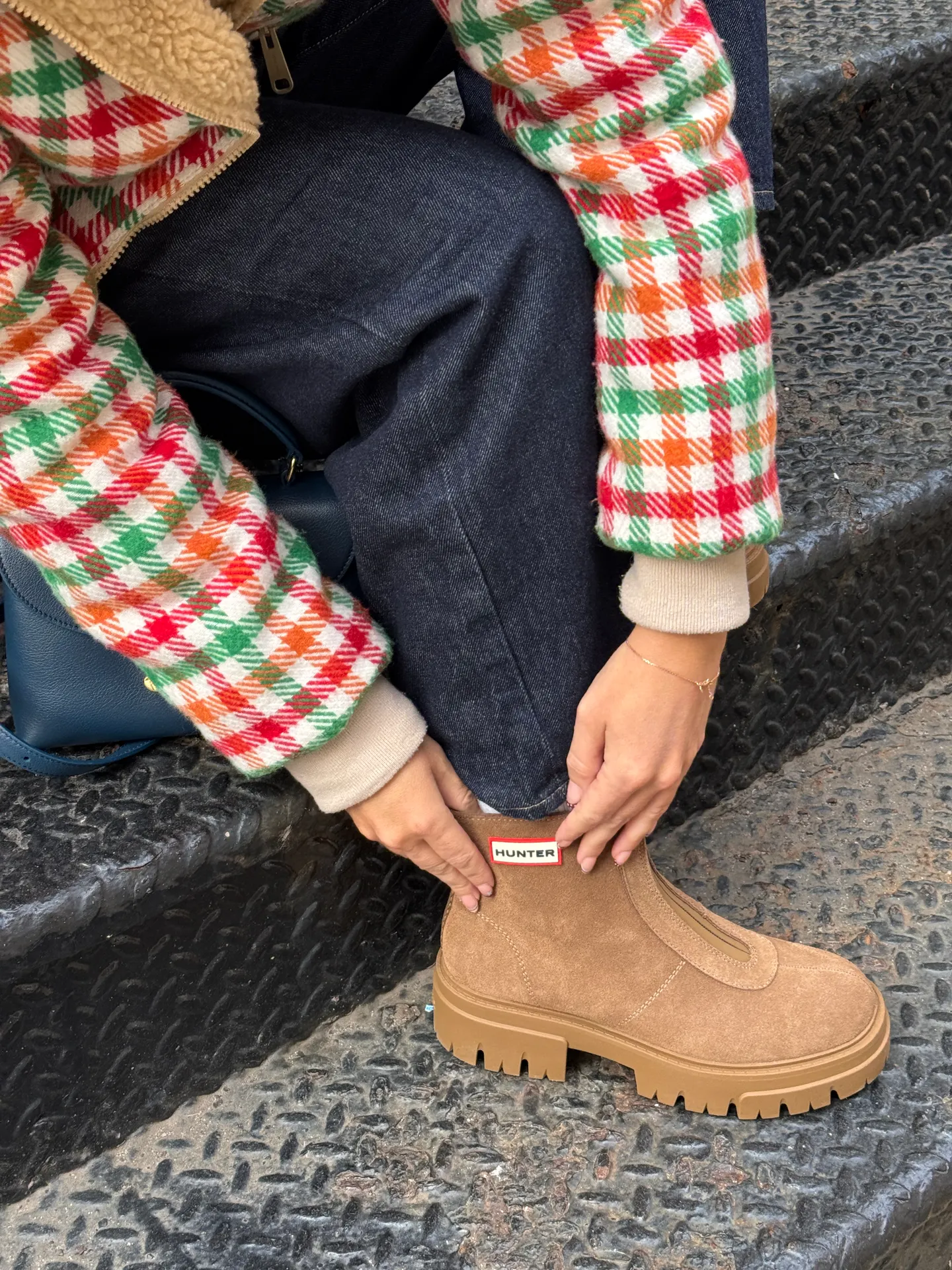 Fuzzy plaid jacket in red, green, orange, white, paired with denim and Hunter boots.