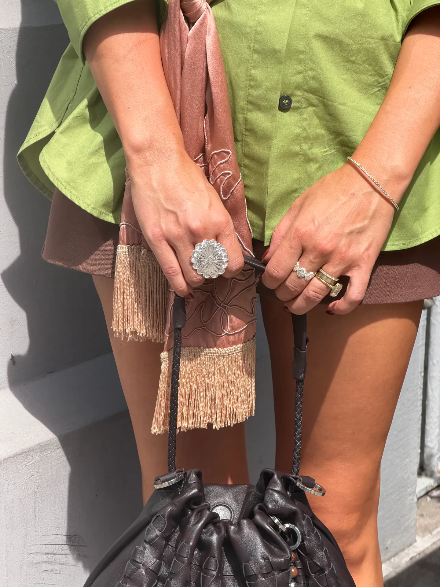 Lime green shirt, brown skirt, fringed scarf, and dark woven leather bag.