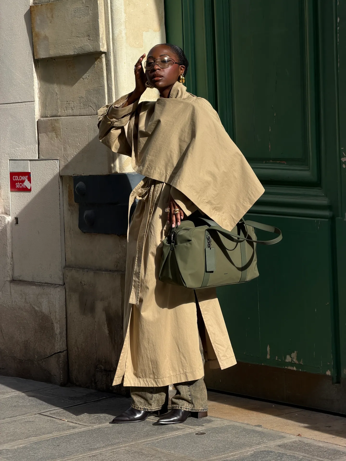 Khaki trench coat, green cargo pants, and a green shoulder bag in sunlight.