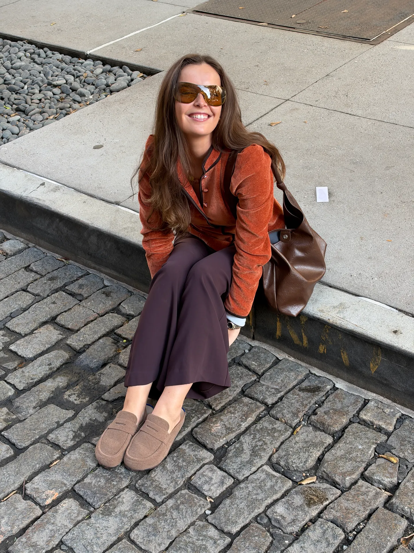 Burnt orange velvet blazer, brown wide-leg pants, and tan loafers on a cobblestone street.