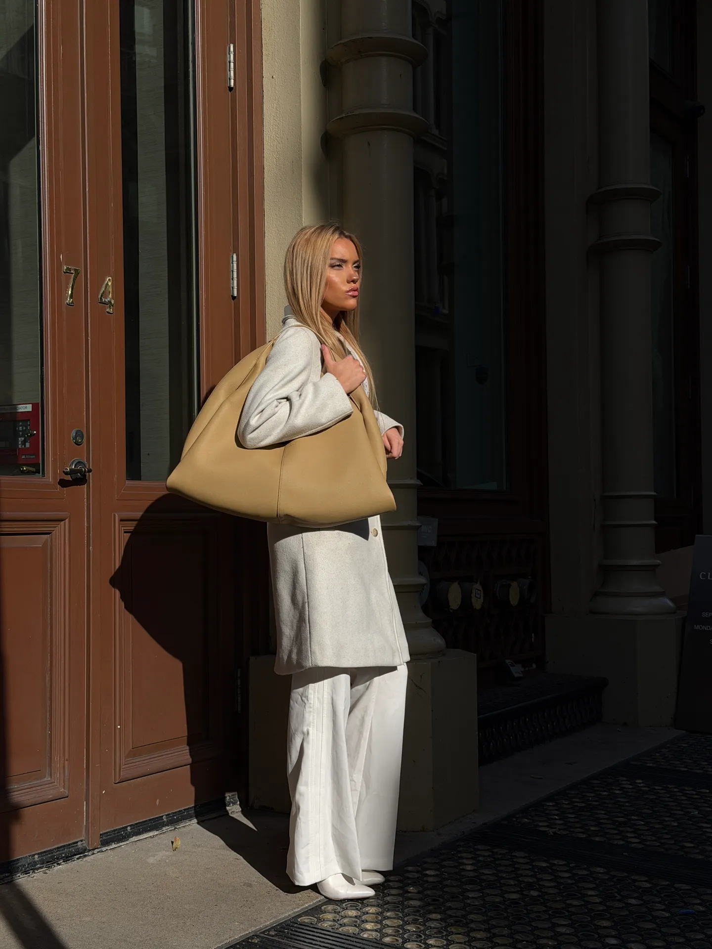 Light gray long coat, white wide-leg pants, and large tan shoulder bag.
