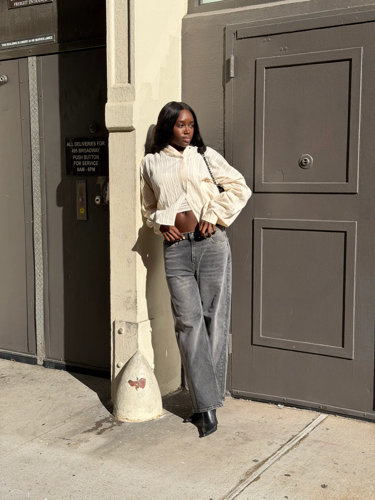 Cream pleated crop top, dark wash loose-fit jeans, and black boots.