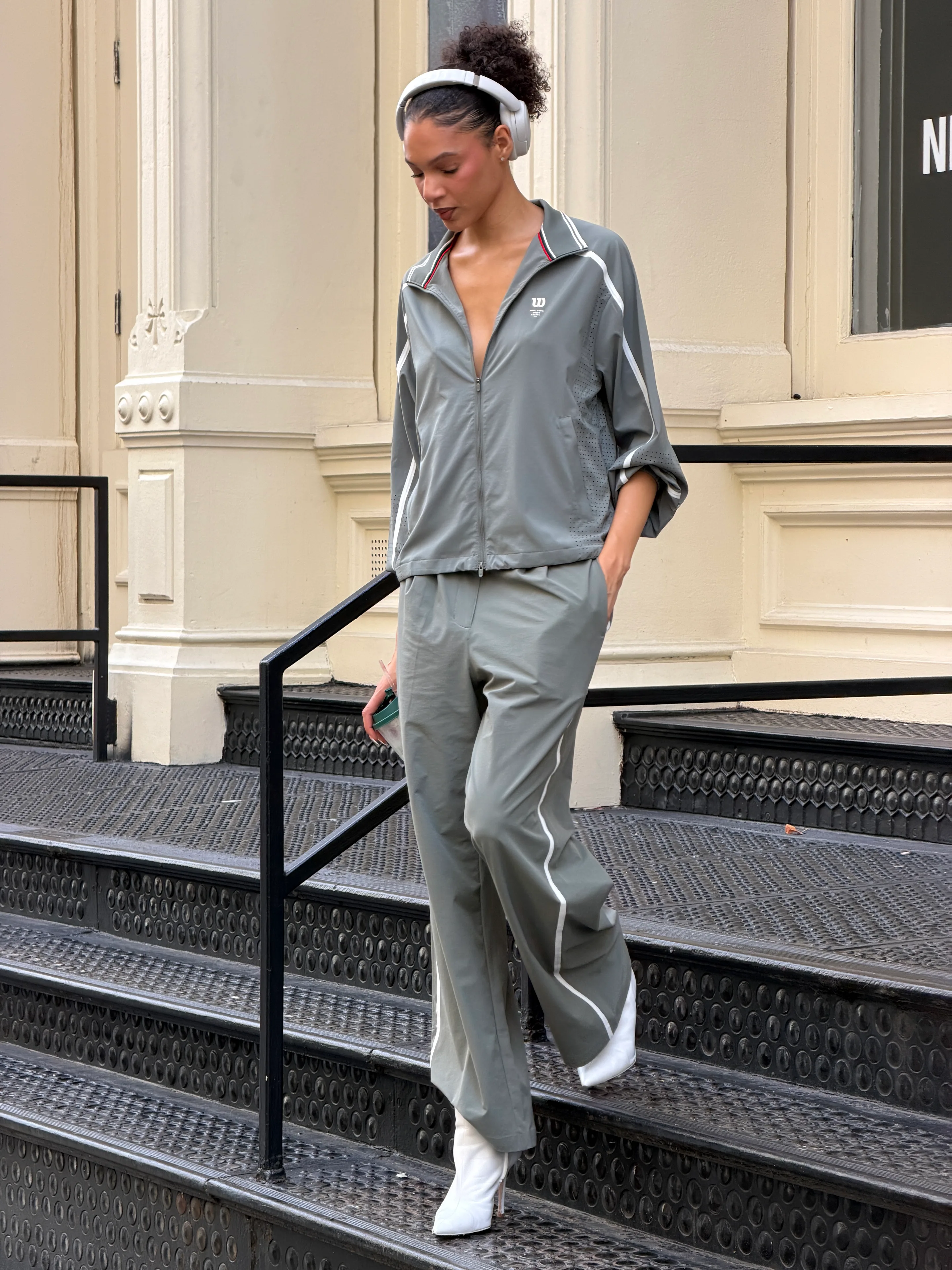 Grey zipped tracksuit with white stripes, white boots, and white headphones.