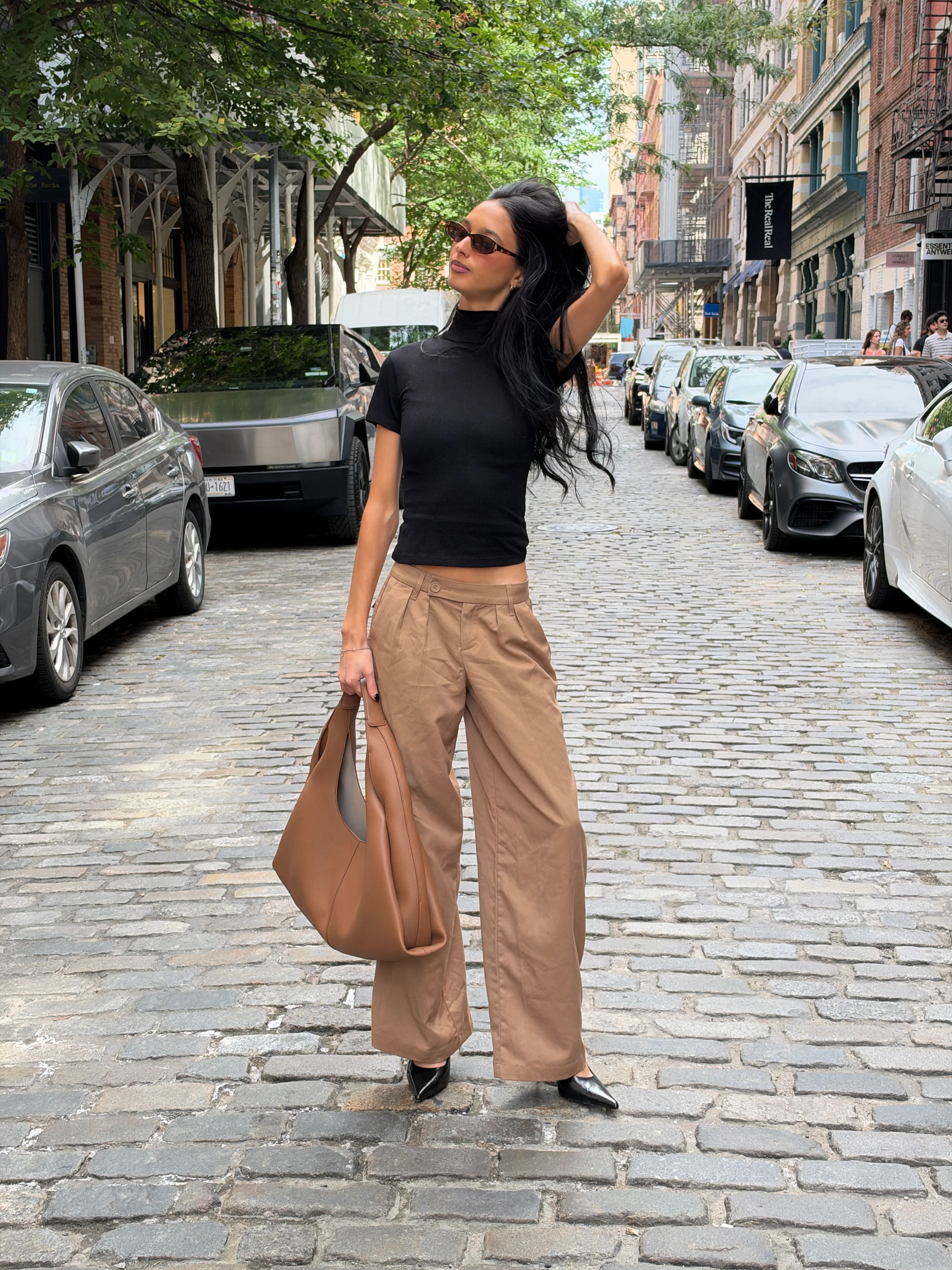 Black ribbed turtleneck top, wide-leg khaki pants, and a brown leather bag.