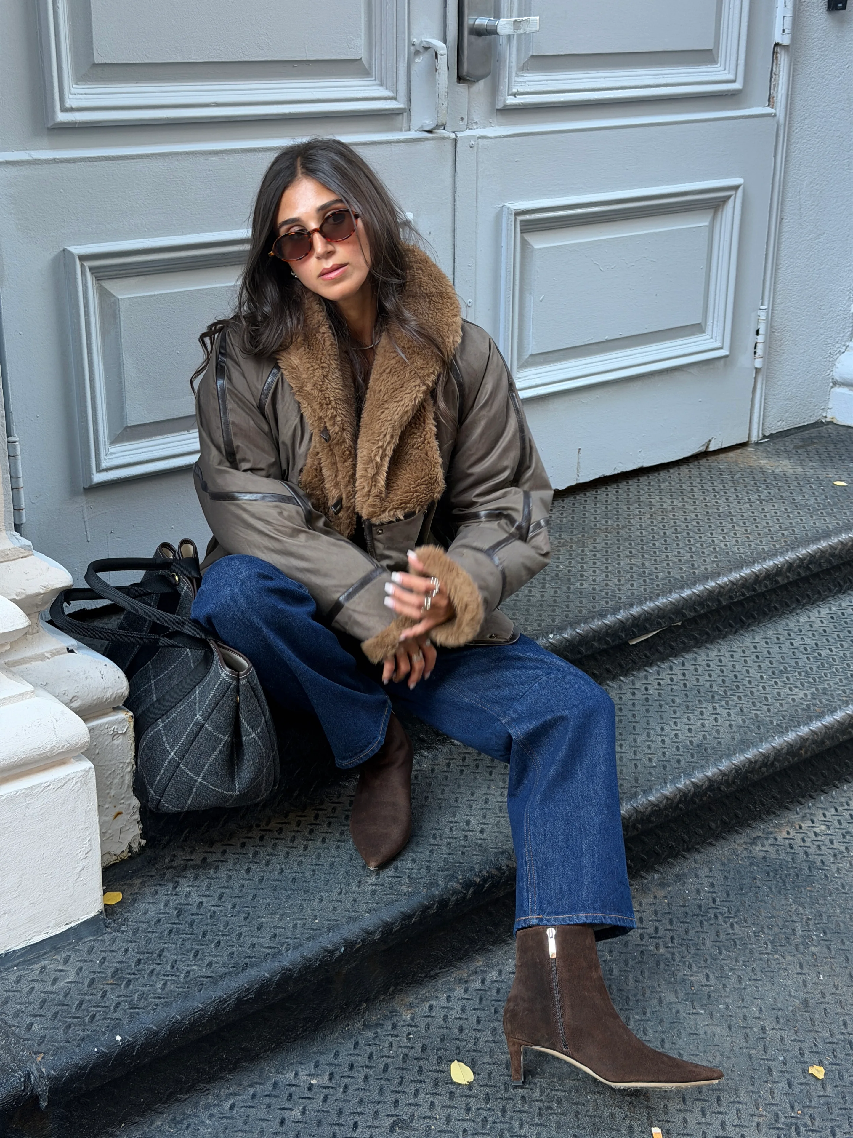 Brown bomber jacket with fur collar, blue jeans, and brown suede ankle boots.