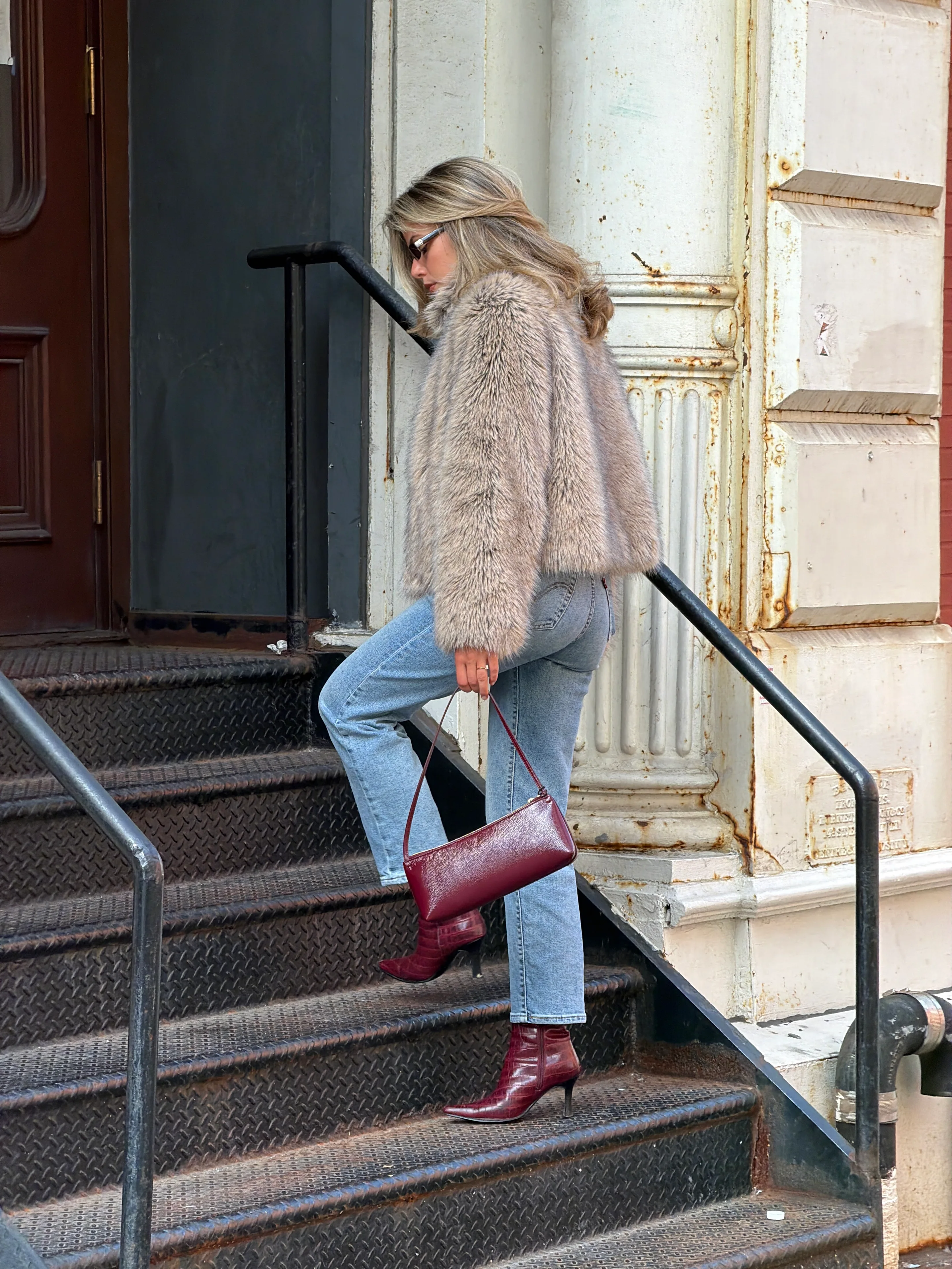 Beige faux fur jacket, light wash jeans, and burgundy croc-embossed boots and bag.