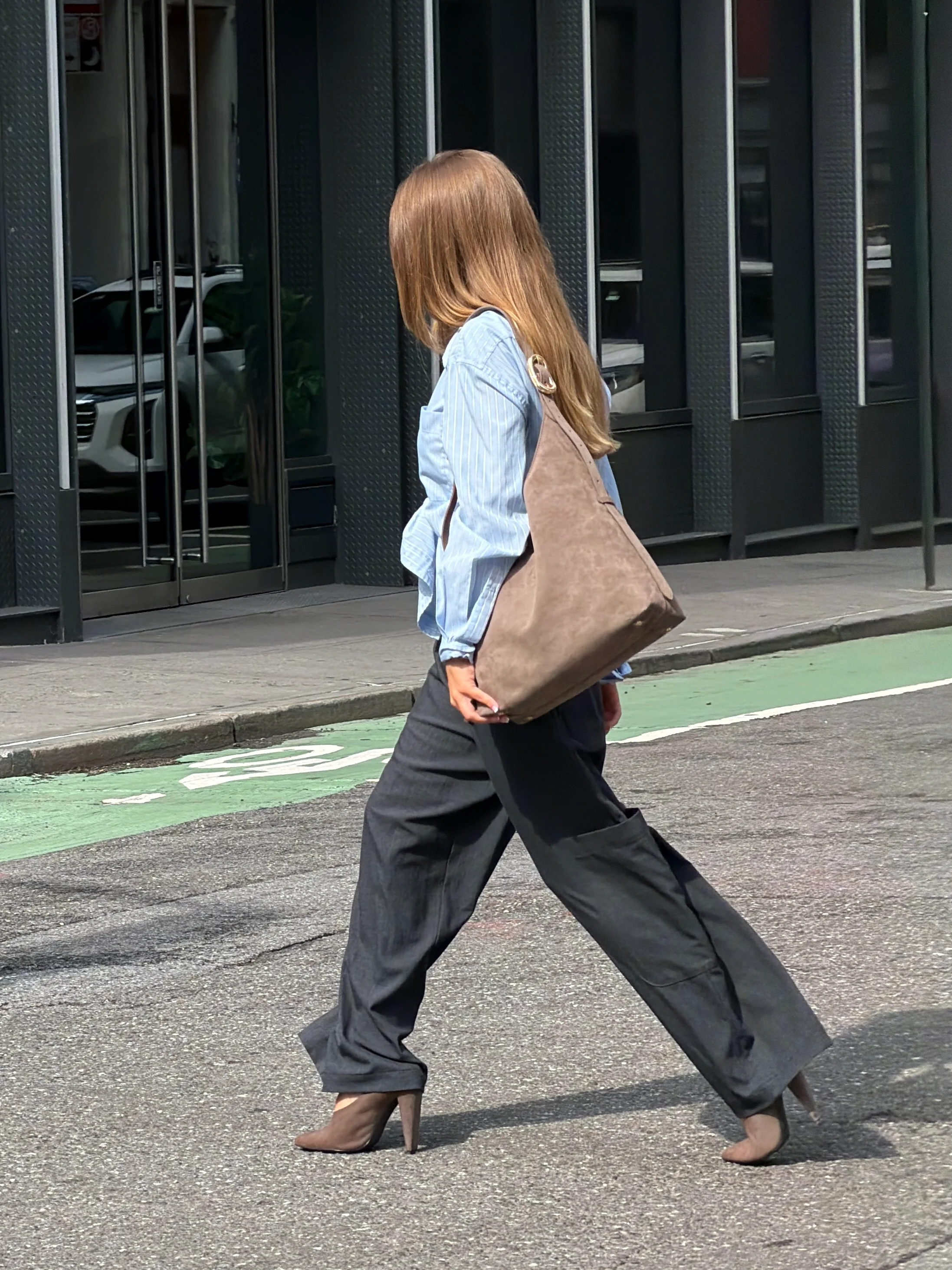 Light blue pinstripe shirt, charcoal wide-leg pants, brown suede bag, and matching heels on a street.