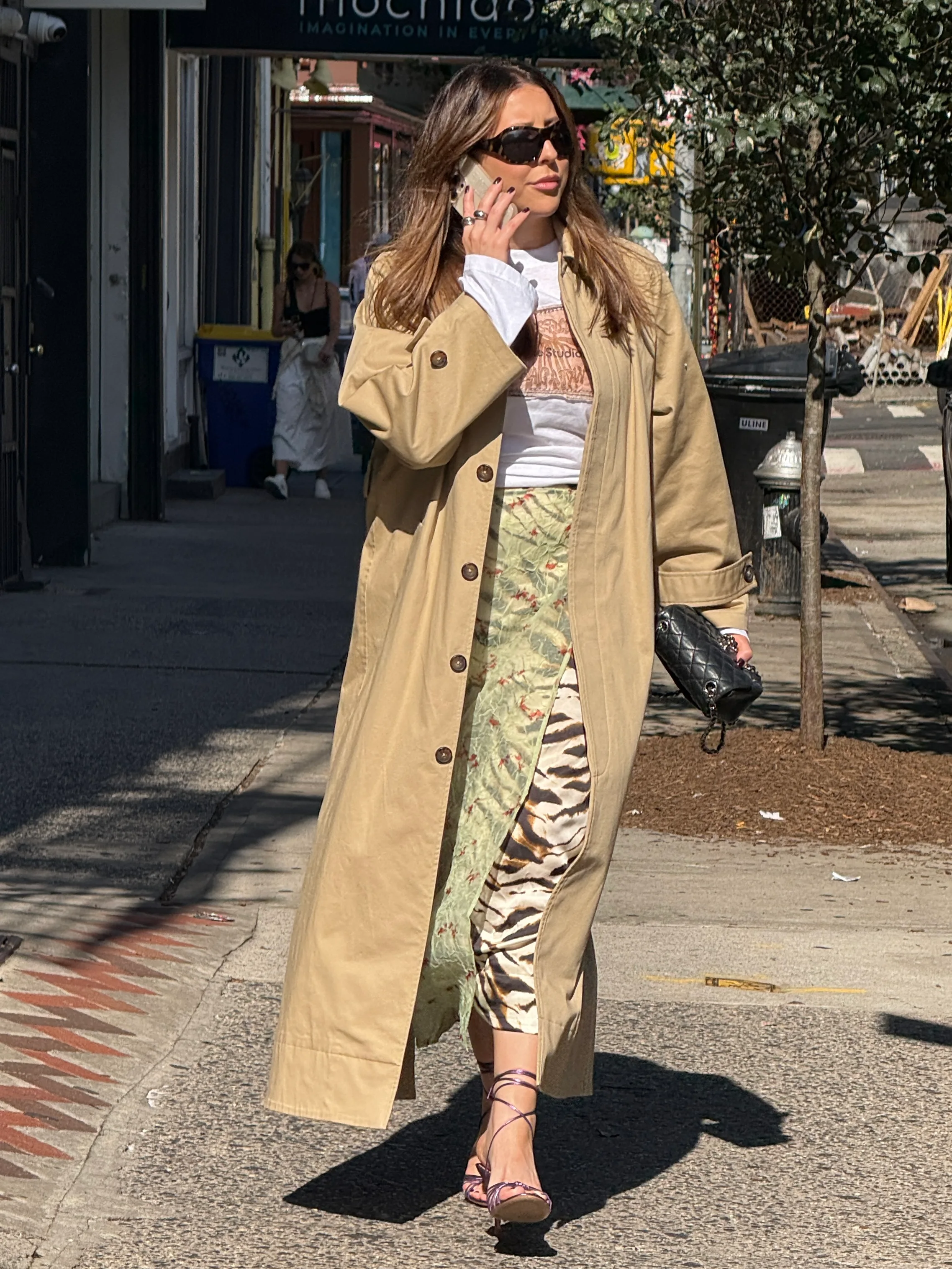 Khaki trench coat over a layered top and a tiger-print skirt with lace-up sandals.