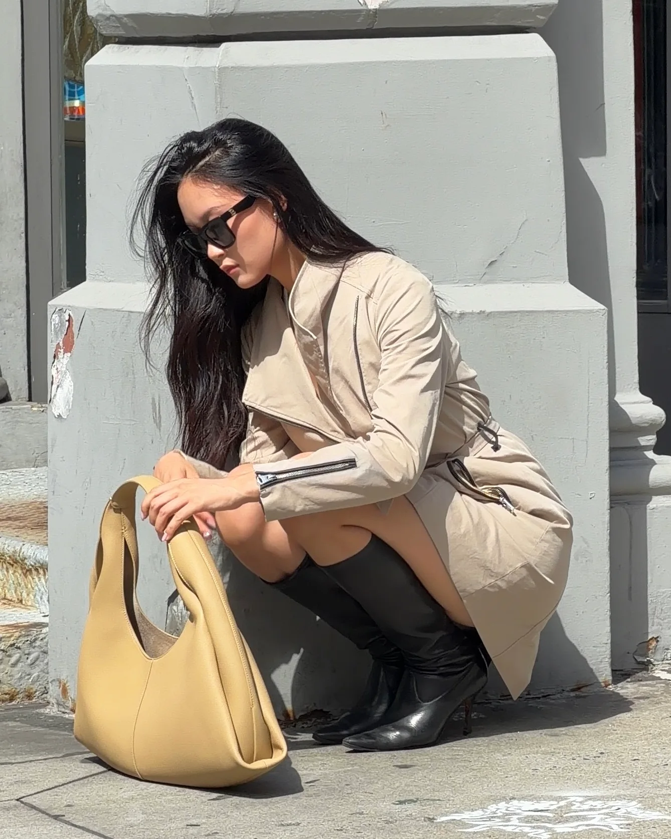 Beige trench dress, black knee-high boots, and a matching beige handbag.