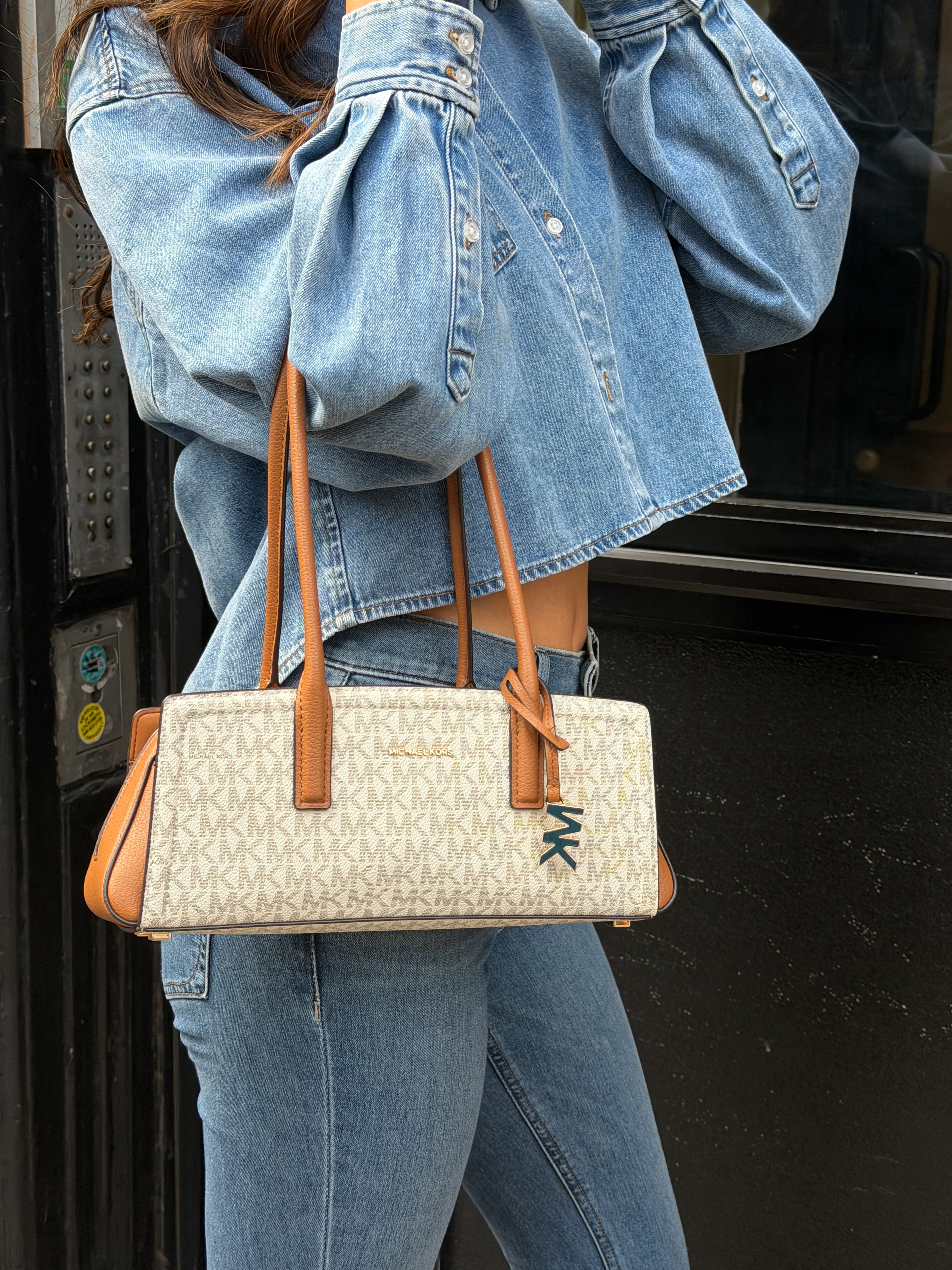 Light blue cropped denim jacket with puffy sleeves and matching jeans, holding a Michael Kors monogram bag.