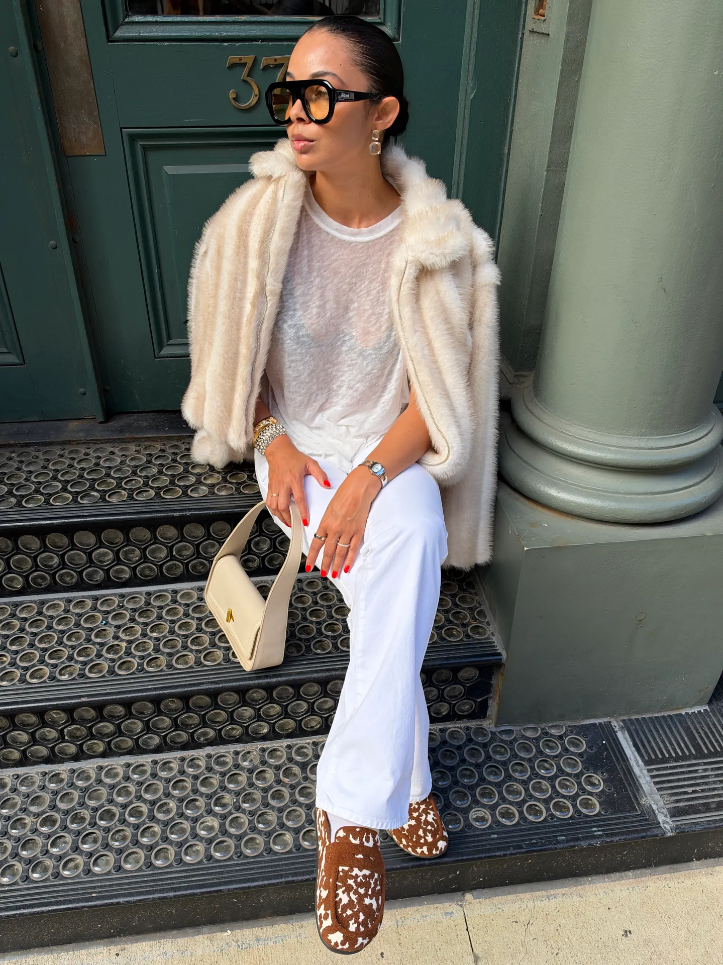 Cream faux fur jacket, white tee & pants, cow print shoes, black sunglasses, beige bag.
