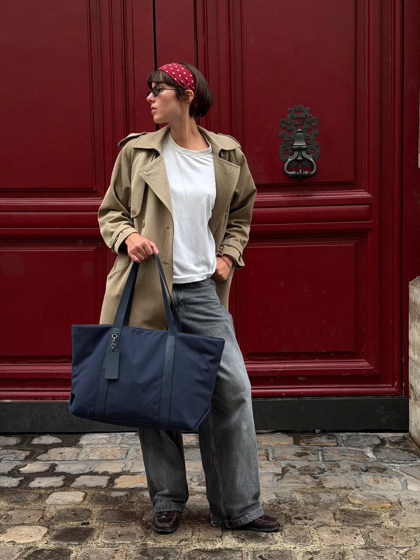 Khaki trench coat, white tee, grey jeans, blue tote bag, and red bandana.