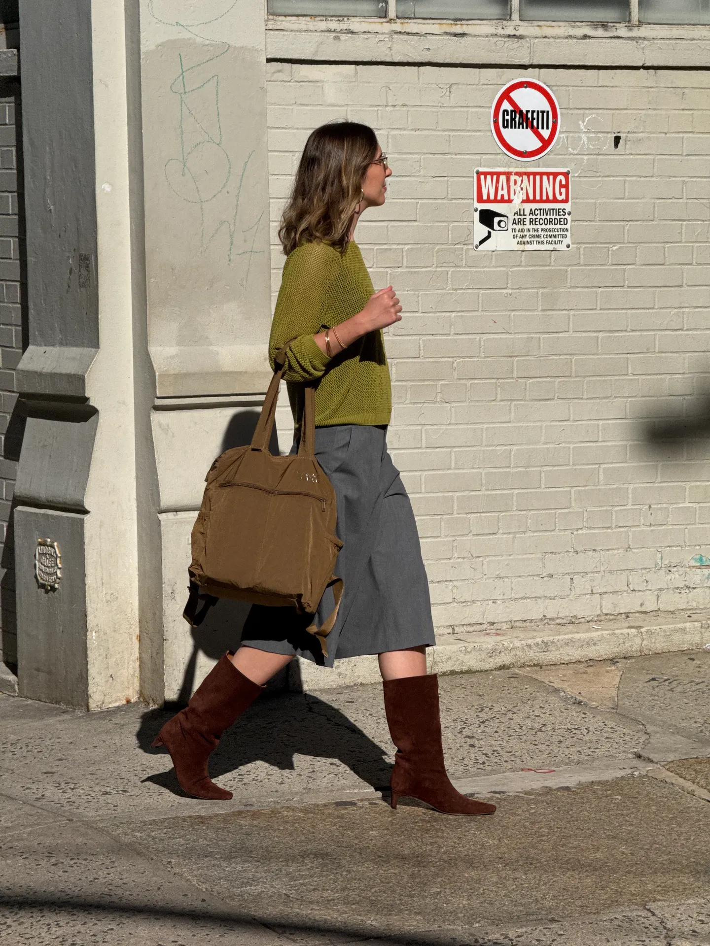 Olive green knit sweater, grey culottes, brown suede boots, and a brown tote bag.