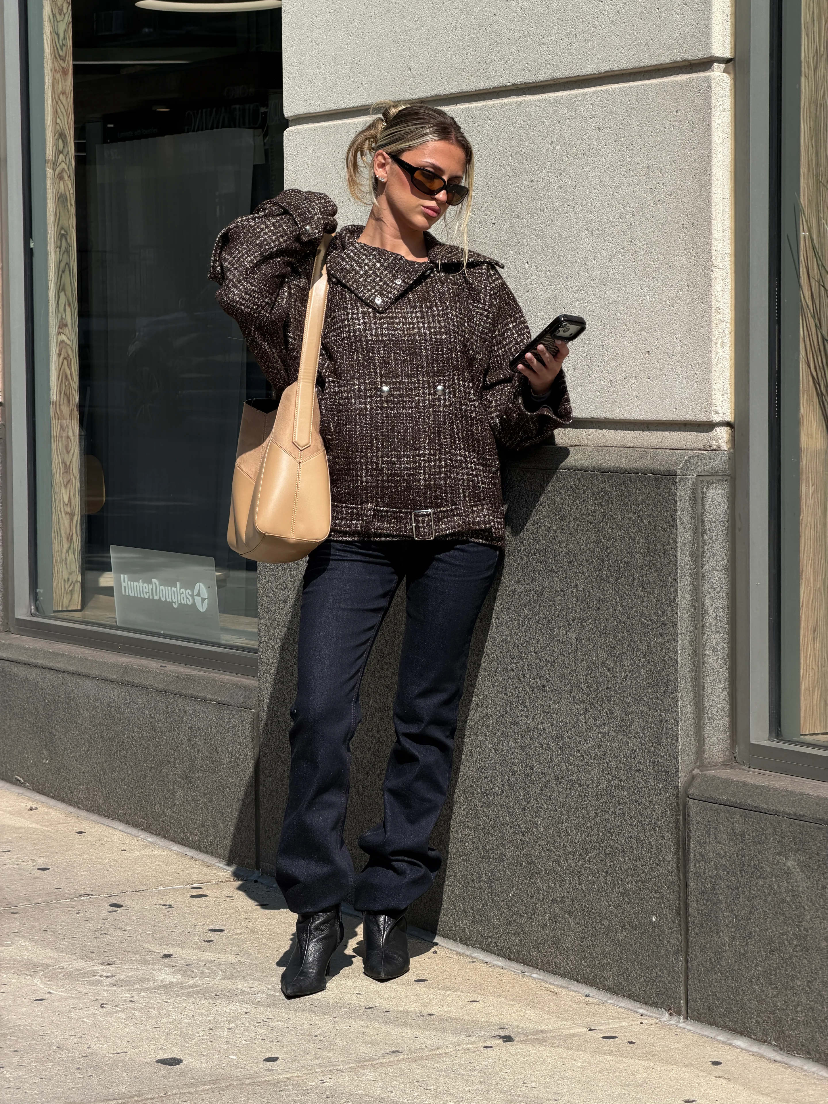 Brown tweed jacket with dark wash jeans, black pointed-toe boots, and a beige shoulder bag.