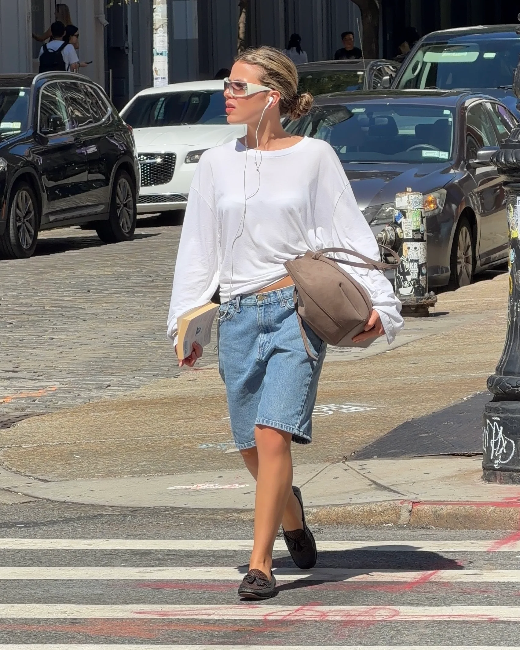 White oversized shirt, denim jorts, black loafers, sunglasses, and a brown bag.